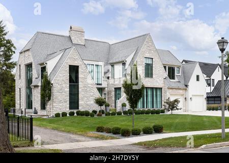 Ein luxuriöses, modernes Bauernhaus mit einem Stein und einer vertikalen Platte und einem Batten-Abstellgleis, großen Fenstern und einer wunderschönen Landschaft. Stockfoto