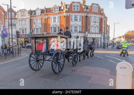 November 2021. Southend on Sea, Großbritannien. Trauerprozession für Sir David Amess Parlamentsabgeordnete mit einem traditionellen Pferdewagen mit einem Sarg, der von Union Jack überzogen wird, führt an der Hamlet Court Road, Westcliff on Sea vorbei. Das Cortege besteht aus formell gekleideten Fahrern in Top-Hüten, vier schwarzen Pferden und einer Motorrad-Eskorte der Polizei. Der feierliche Tribut ging durch die Straßen der Stadt, die von Backsteinhäusern und Zuschauern gesäumt waren, und spiegelte die öffentliche Trauer und den Respekt der Bürger vor dem verstorbenen Parlamentsabgeordneten wider. Penelope Barritt/Alamy Live News Stockfoto