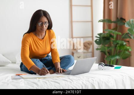 Afroamerikanische Frau Mit Laptop Und Notizen Im Schlafzimmer Stockfoto