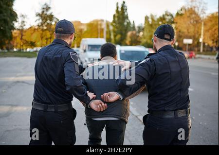 Zwei männliche Polizisten verhaften einen jungen Mann Stockfoto