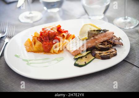 Tagliatelle mit Tomaten und einem Lachsfilet mit gegrilltem Gemüse Stockfoto