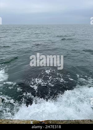 Wellen waschen sich über dem Betonsteg im Meer Stockfoto
