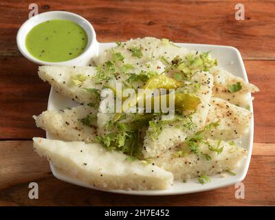 Khaman weiß Dhokla aus Reis oder Urad dal ist ein beliebtes Frühstück oder Snacks Rezept aus Gujarat, Indien, serviert mit Green Chutney und gebratenen Chill Stockfoto