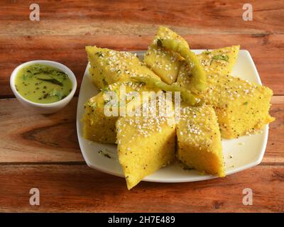 Khaman Dhokla aus Reis oder Urad dal ist ein beliebtes Frühstück oder Snacks Rezept aus Gujarat, Indien, serviert mit Green Chutney und gebratenen Chili.. Se Stockfoto