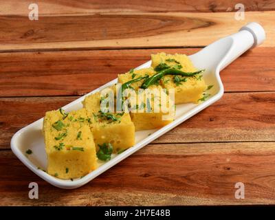 Khaman Dhokla aus Reis oder Urad dal ist ein beliebtes Frühstück oder Snacks Rezept aus Gujarat, Indien, serviert mit Green Chutney und gebratenen Chili.. Se Stockfoto