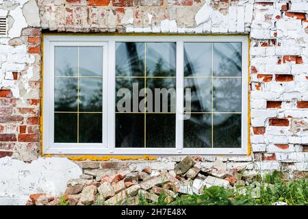 Neues rechteckiges Fenster in einer alten roten Backsteinmauer. Aus dem Fenster der Welt-Serie. Stockfoto