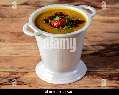 Authentische indische beliebte Speisen Dal Tadka Curry oder traditionelle indische Suppenlentile auf rustikalem Holzhintergrund. Selektiver Fokus Stockfoto