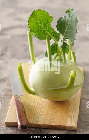 Ein Kohlrabi mit Blättern auf einem hölzernen Brett Stockfoto