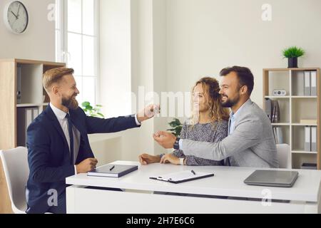 Lächelnd männlich makler geben Schlüssel zu paar Käufer Stockfoto