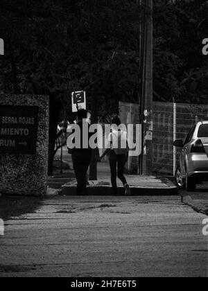 TUXTLA GUTIERREZ, MEXIKO - 14. Sep 2021: Eine Graustufenaufnahme eines Paares, das Hand in Hand in Hand in den Straßen Mexikos herumläuft Stockfoto