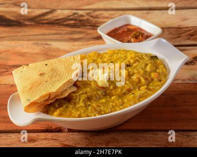 Dal khichdi oder Khichadi, leckere indische Rezept serviert in Schüssel über rustikalen Holzhintergrund, das Essen aus Dal und Reis mit ganzen Gewürzen kombiniert, o Stockfoto