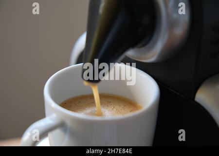 Nahaufnahme einer Kaffeemaschine, die einen Espresso in eine Tasse gießt. Stockfoto