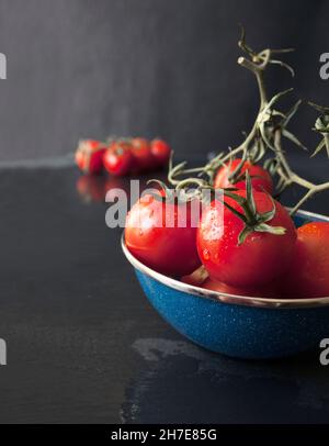 Frisch gewaschene, gereifte Tomaten aus der Rebe in einer Blue Enamel Bowl Stockfoto