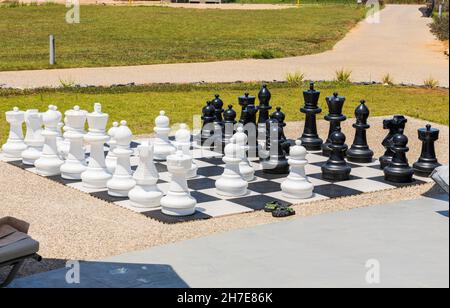 Schachbrett mit riesigen schwarz-weißen Schachfiguren für Freiluftspiele am Strand. Griechenland. Stockfoto