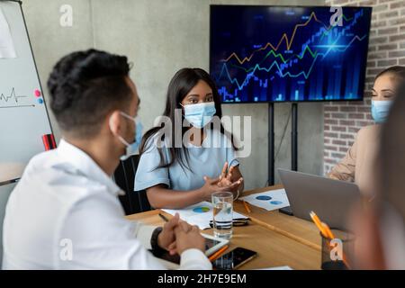 Multiethnische Mitarbeiter, Die Ein Schützendes Gesicht Tragen, Treffen Sich Im Konferenzraum Im Büro Stockfoto