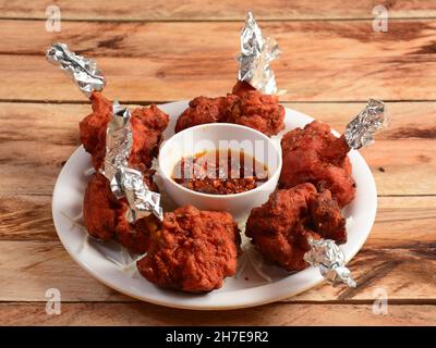 Chicken Lollipop ist eine indische, chinesische Vorspeise, serviert auf einem rustikalen Holzhintergrund. Selektiver Fokus Stockfoto