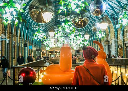 London, Großbritannien. 22nd. November 2021. Fröhlicher Ballonhund von Castle Fine Art, der Geld an die Tierschutzorganisation Blue Cross gibt - Menschenmassen durchstöbern die Geschäfte und beobachten Straßenunterhalter unter dem weihnachtsbaum, riesige Misteln und andere Lichter in einem belebten Covent Garden, wenn der Weihnachtsanlauf beginnt. Kredit: Guy Bell/Alamy Live Nachrichten Stockfoto