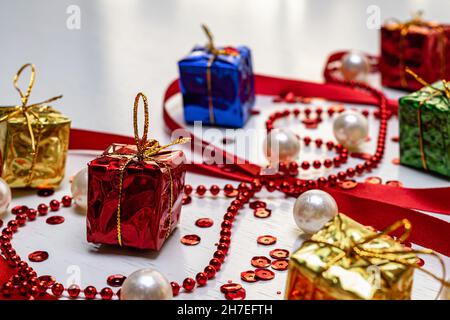 Bunte Weihnachtsgeschenke und -Dekorationen auf weißem Holzhintergrund. Horizontales Foto. Stockfoto