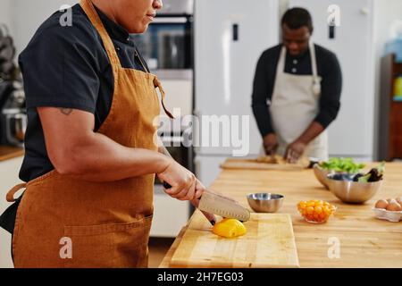 Seitenansicht bei zwei Köchen, die Gemüse schneiden, während sie in der professionellen Küche arbeiten, Kopierfläche Stockfoto