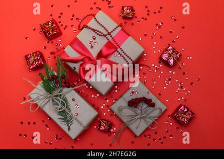 Weihnachtsgeschenke und helle Weihnachtsbaumdekorationen auf rotem Hintergrund. Rote Spielzeuge und funkelt. Horizontales Foto. Stockfoto