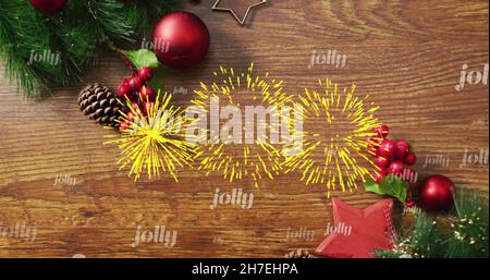 Bild von fröhlichem Text in Wiederholung und Feuerwerk über weihnachtsdekorationen Stockfoto