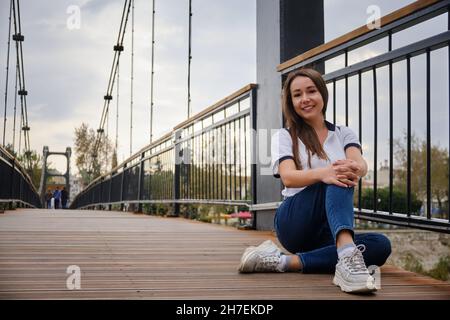 Frau sitzt auf einer Fußgängerbrücke Stockfoto