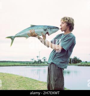 Junger Mann mit einem großen King Fisch, Queensland Australien. Stockfoto