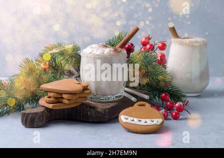 Zwei Gläser mit Eierpunsch, Eierlikör im weihnachtlichen Dekor auf graublauem Hintergrund. Weihnachts-Getränk Ei-Nog mit handgefertigtem Lebkuchen und Bokeh Stockfoto