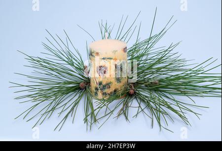 Handbemalte Weihnachtskerze mit immergrünen Tannennadeln. Festliches Licht und Gemütlichkeit für die Neujahrsfeiertage Stockfoto