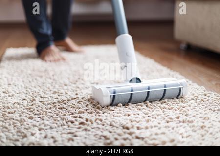 Die Turbo-Bürste eines kabellosen Staubsaugers reinigt den Teppich im Haus in Nahaufnahme. Moderne Technologien für die Reinigung. Stockfoto