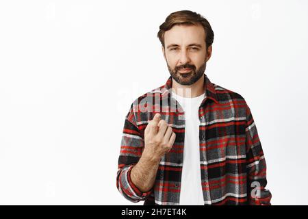 Bild eines hübschen bärtigen Mannes, der mit dem Finger auf die Kamera zeigt, verdächtig schielt, etwas herausstellt, seine Sie-Geste, über weißem Hintergrund stehend Stockfoto