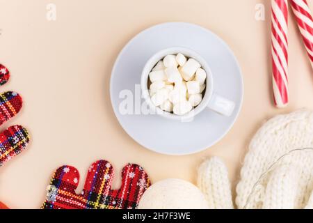 Tasse Kaffee, Geschenkbox und Strickpullover, LED-Leuchten auf beigem Hintergrund. Hygge-Stil, Winterkonzept. Gemütlicher Schreibtisch. Neujahr und Weihnachten Stockfoto