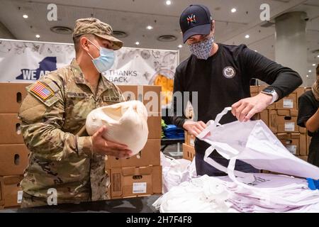 New York City, Usa. 22nd. November 2021. Ein US-Soldat der New Yorker Nationalgarde und ein Freiwilliger unterstützen die Verteilung von Thanksgiving-Truthäuten für bedürftige Familien im Jacob Javits Convention Center am 22. November 2021 in New York City. Quelle: Darren McGee/New York National Guard/Alamy Live News Stockfoto