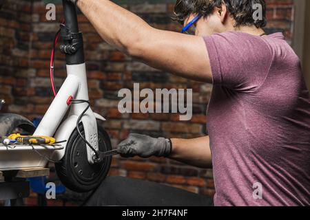 Mechanisches Anziehen der Bremsmutter am Rad eines Elektrorollers in seiner Werkstatt Stockfoto