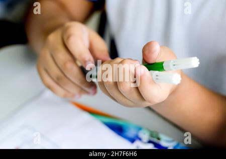 Hände, die Wachsmalstifte zum Zeichnen auf Papier aufheben. Salvador, Bahia, Brasilien. Stockfoto
