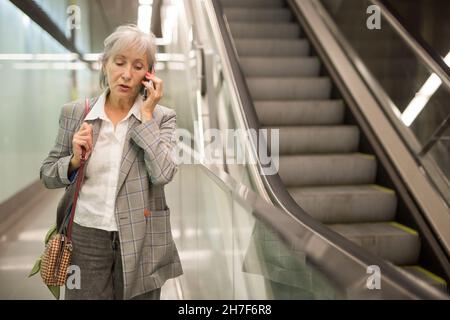 Eine ältere Dame, die im Einkaufszentrum telefonische Gespräche geführt hat Stockfoto