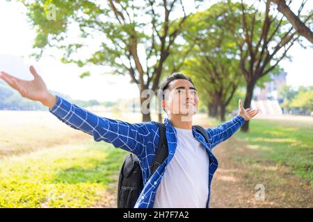 Glücklicher Mann, der tief frische Luft in einem Wald mit grünen Bäumen atmet Stockfoto