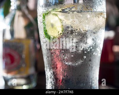 Glas kaltes Sodawasser mit Eiswürfeln und einer Scheibe Kalk, außen Tau. Geringe Schärfentiefe mit der Außenseite des Glases im Fokus. Stockfoto