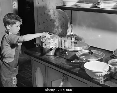 Young Boy überprüft Töpfe mit Lebensmitteln auf dem Herd für das Thanksgiving-Abendessen, Ledyard, Connecticut, USA, Jack Delano, U.S. Farm Security Administration, Fotosammlung des US Office of war Information, November 1940 Stockfoto