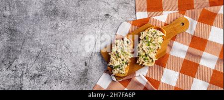 Thunfischsalat, offene Sandwiches auf einem kleinen Holzbrett auf dunkelgrauem Hintergrund. Draufsicht, flach liegend Stockfoto