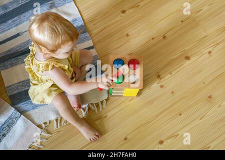 Happy girl Kleinkind Schlagen Holzhammer auf farbigen Kugeln frühe Entwicklung ökologischen Spielzeug Stockfoto