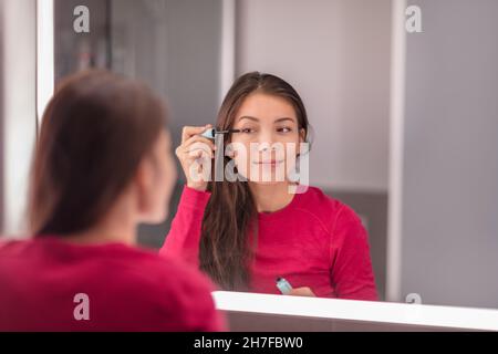 Frau setzen Make-up in der LED beleuchteten Spiegel immer bereit Morgen Beauty-Routine Anwendung Mascara Auge Make-up. Asiatische Mädchen zu Hause Lifestyle Stockfoto