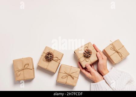 Weibliche Hände halten ein Geschenk in Papier umweltfreundliche Verpackung. Geschenk für Weihnachten oder Neujahr DIY Verpackung Stockfoto