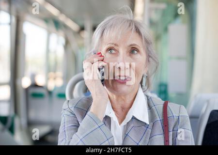Porträt einer älteren Frau, die in der Straßenbahn telefoniert Stockfoto
