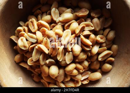 Draufsicht auf eine Handvoll geschälte Erdnüsse in einer Holzschale Stockfoto
