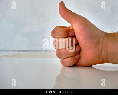 Hand und ihre Schatten und Reflexion auf der gemusterten Wand von OKAY Zeichen von Hand gemacht. Stockfoto