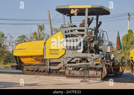 Phayao, Thailand - 27. Jan 2021: Gelber Asphalt-Pfandgänger und ein Arbeiter auf der Asphalt-Straße Stockfoto