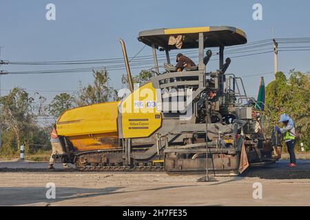 Phayao, Thailand - 27. Januar 2021: Asphaltfertiger und LKW und drei Arbeiter arbeiten auf der Straße Stockfoto
