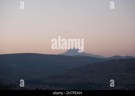 Berggipfel von Erciyes, indem man in Kappadokien am frühen Morgen bei Sonnenaufgang Fotos von den Kaminen von drei Schönheiten (uc guzeller) machte Stockfoto