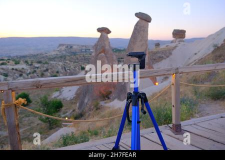 Blaues Stativ, das am frühen Morgen während des Sonnenaufgangs auf dem Balkon in drei Schönheiten (uc guzeller) in Kappadokien steht, um Naturaufnahmen zu machen Stockfoto